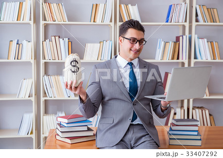 Businessman in library with a money sack and a 33407292