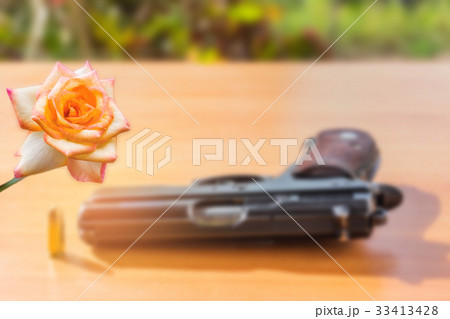 Rose with blurred the gun and bullet on the wooden Rose with blurred the gun and bullet on the wooden 33413428