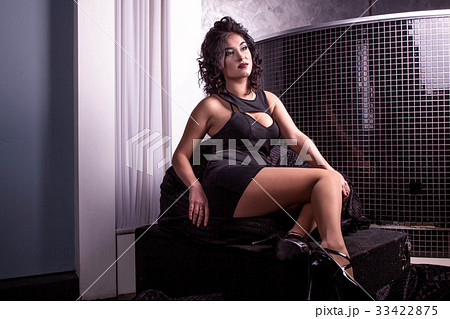 Pretty woman in a short black dress sitting on a 33422875