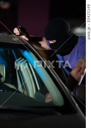 Closeup of criminal man with a gun in car parking 33425149