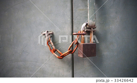 Old rust lock key with chain on grey cement wall. 33426642