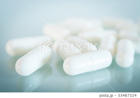 White medical capsules lie on the mirror surface White medical capsules lie on the mirror surface 33467324