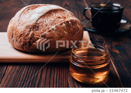 Bread, cup of tea and honey on a brown table 33467472