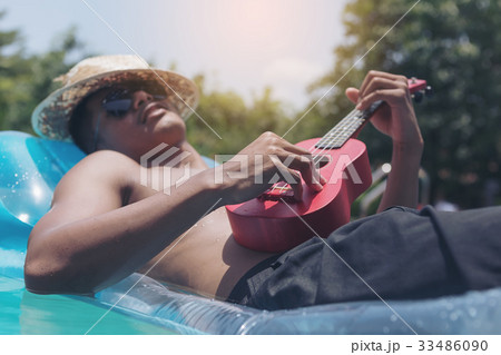 The young man relaxes and plays Ukulele on rubber The young man relaxes and plays Ukulele on rubber 33486090