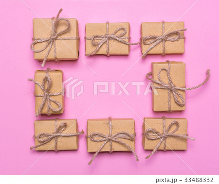 A frame of gift boxes wrapped in kraft paper on a pink background.Flat lay design, top view 33488332
