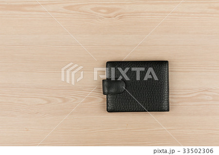 Black leather purse lying on a wooden table. 33502306
