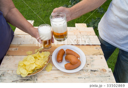 hands holding glasses with beer, chips and 33502869