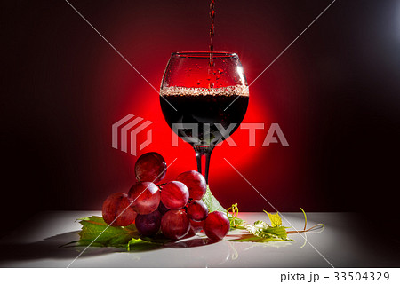 pouring glass of red wine and grapevine with  leaf 33504329