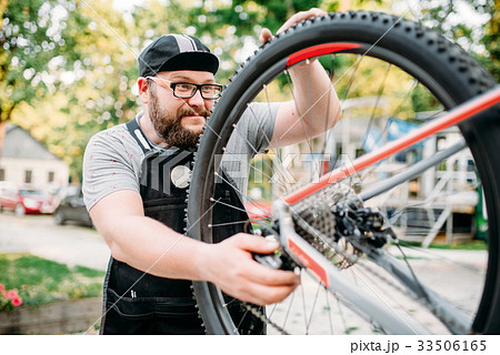 Bicycle repairman works with bike wheel 33506165
