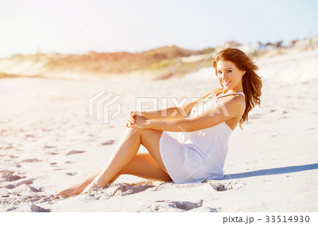 Young woman sitting on the beach 33514930