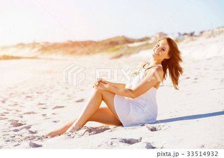 Young woman sitting on the beach 33514932