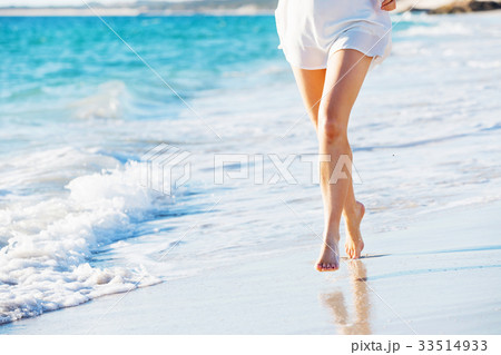 Young woman walking along the beach 33514933