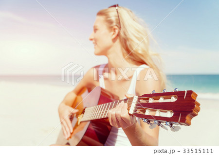 Beautiful young woman playing guitar on beach Beautiful young woman playing guitar on beach 33515111