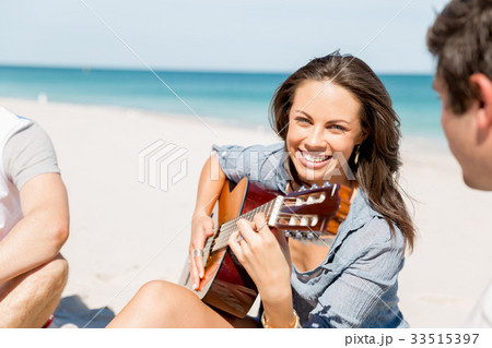 Beautiful young woman playing guitar on beach Beautiful young woman playing guitar on beach 33515397