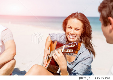 Beautiful young woman playing guitar on beach Beautiful young woman playing guitar on beach 33515398