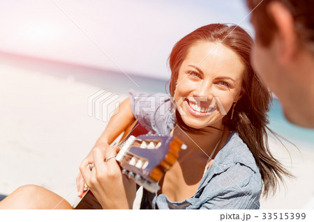 Beautiful young woman playing guitar on beach Beautiful young woman playing guitar on beach 33515399
