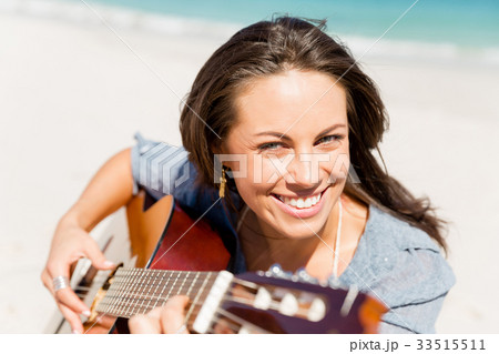 Beautiful young woman playing guitar on beach Beautiful young woman playing guitar on beach 33515511