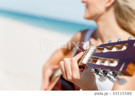 Beautiful young woman playing guitar on beach 33515589