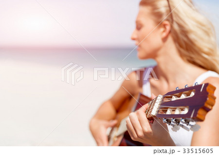 Beautiful young woman playing guitar on beach 33515605