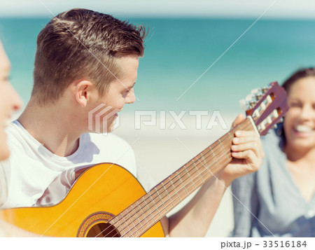 Young man playing guitar on beach Young man playing guitar on beach 33516184