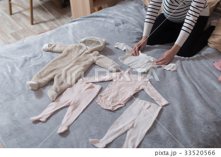 Baby's clothes laid out on bed, natural light. 33520566