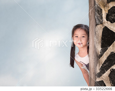 Asian girl hiding behind the wall, peekaboo action Asian girl hiding behind the wall, peekaboo action 33522666