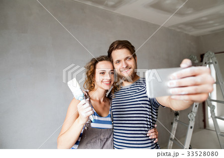 Couple at home painting walls, taking selfie with 33528080