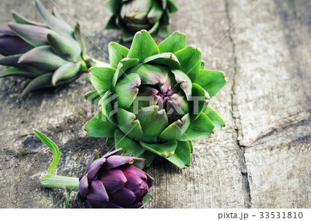 Green and purple artichokes on rustic wooden Green and purple artichokes on rustic wooden 33531810