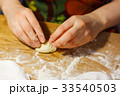 A woman is making dough patties on table flour 33540503