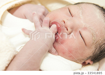 指しゃぶりをする生まれたての赤ちゃんの写真素材