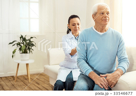 Smart serious doctor sitting behind her patient 33546677