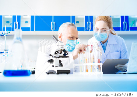 Attentive female scientist examining pink liquid Attentive female scientist examining pink liquid 33547397