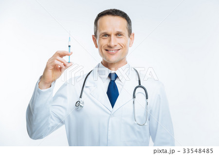 Cheerful doctor posing with syringe for camera 33548485