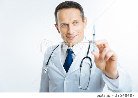 Satisfied doctor checking syringe before injection Satisfied doctor checking syringe before injection 33548487