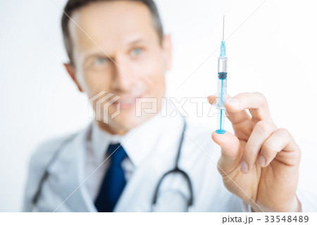 Scaled up shot of male doctor holding syringe with Scaled up shot of male doctor holding syringe with 33548489