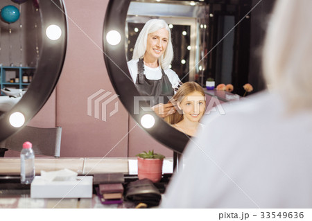 Senior hairdresser braiding her teenage clients 33549636
