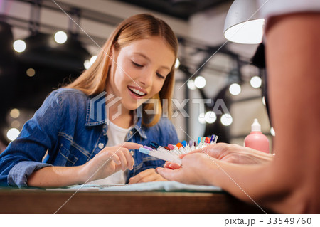 Cheerful girl choosing her future nail color from 33549760