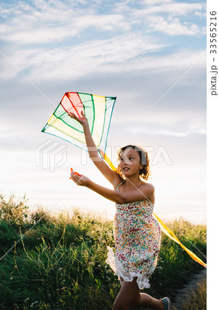 Girl holding kite and running in field 33565216