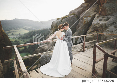 Gorgeous bride and stylish groom walking at sunny 33568226