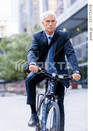 Successful businessman riding bicycle Successful businessman riding bicycle 33575458