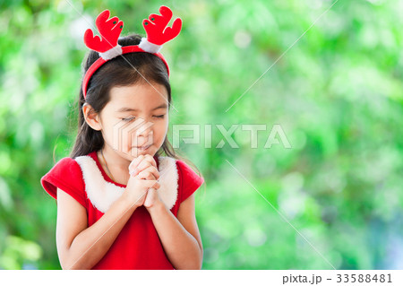 asian girl in christmas dress closed her eyes 33588481