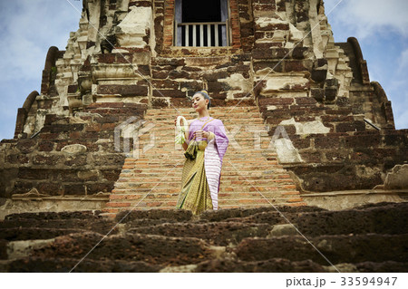 A picture of a Thai woman standing on a stair of a temple 33594947