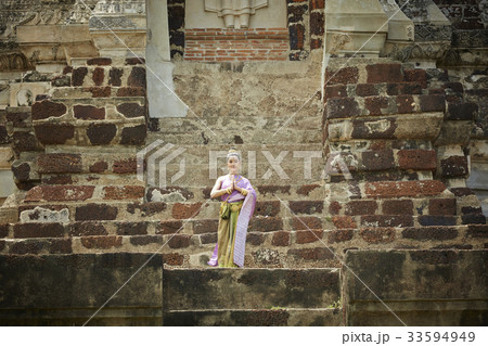 A Thai woman is posing with Thai greeting style at a temple 33594949