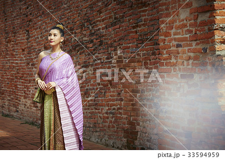 a picture of a Thai girl standing in front of a brick wall 33594959