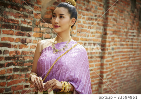 a Thai young woman is standing near by a brick wall a Thai young woman is standing near by a brick wall 33594961