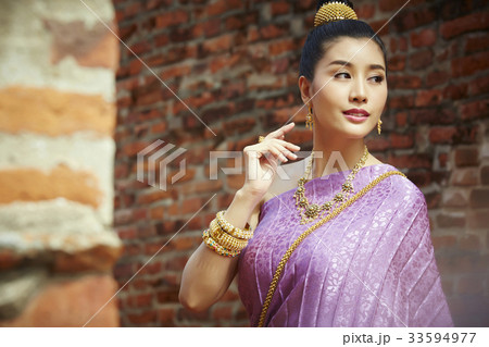 a thai woman in traditional costume is looking at something 33594977