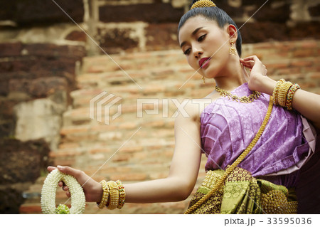 a female dancer in Thai traditional costume is performing outdoors a female dancer in Thai traditional costume is performing outdoors 33595036