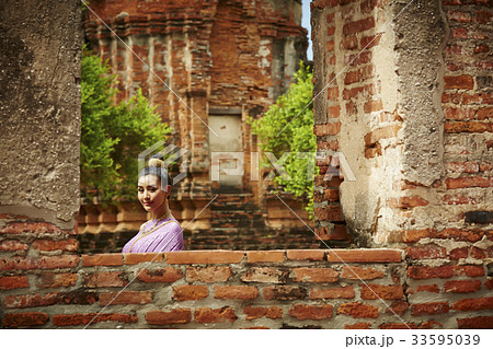 a young woman is standing in historical park and looking at the camera 33595039
