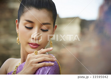 a thai model is dressed in traditional costume and posing outdoors 33595042