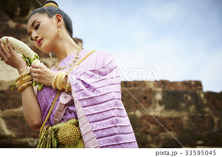 thai woman is standing in historical park while looking flower garland on her hands thai woman is standing in historical park while looking flower garland on her hands 33595045